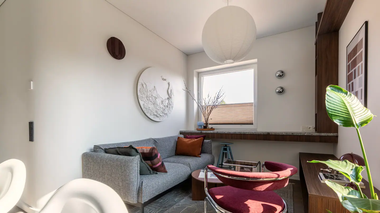 Kleines, helles Wohnzimmer mit grauem Sofa und rotem Sessel